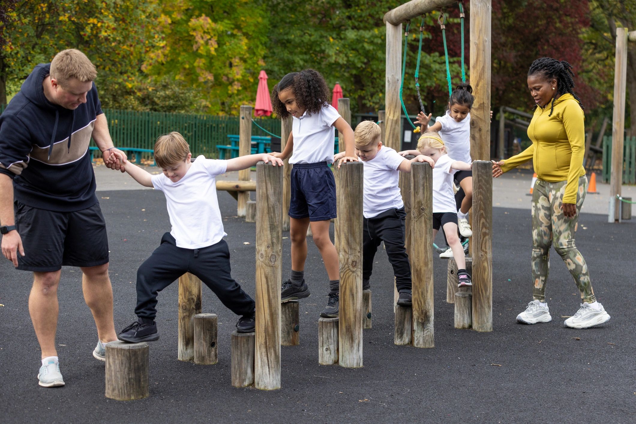 Children participating in an outdoor activity course with teachers supervising