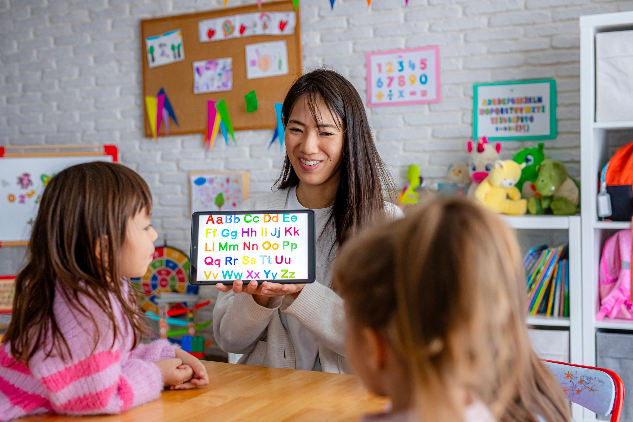 Preschool teacher teaching alphabet letters to children