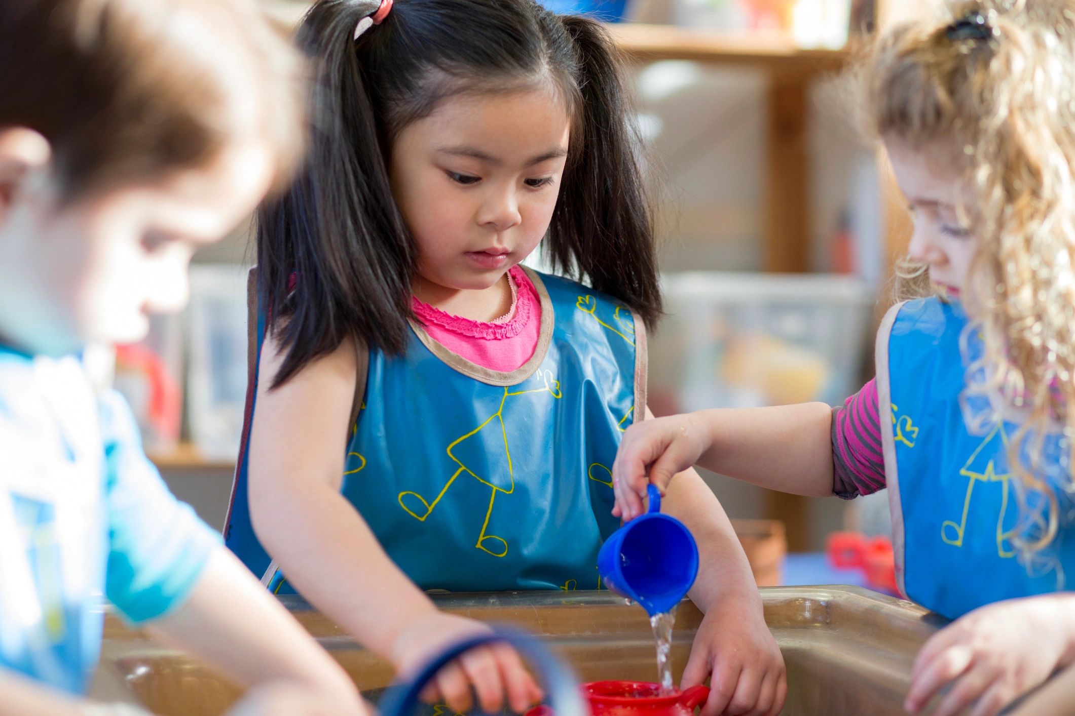 Young children playing together at a water table in nursery